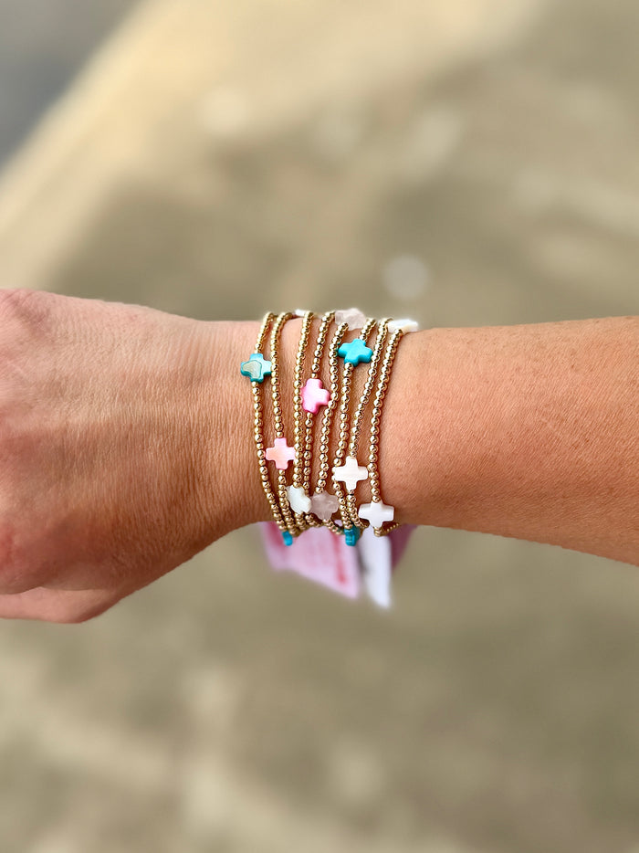 Gold filled and colorful gemstone cross beaded bracelets stacked on a wrist for everyday wear
