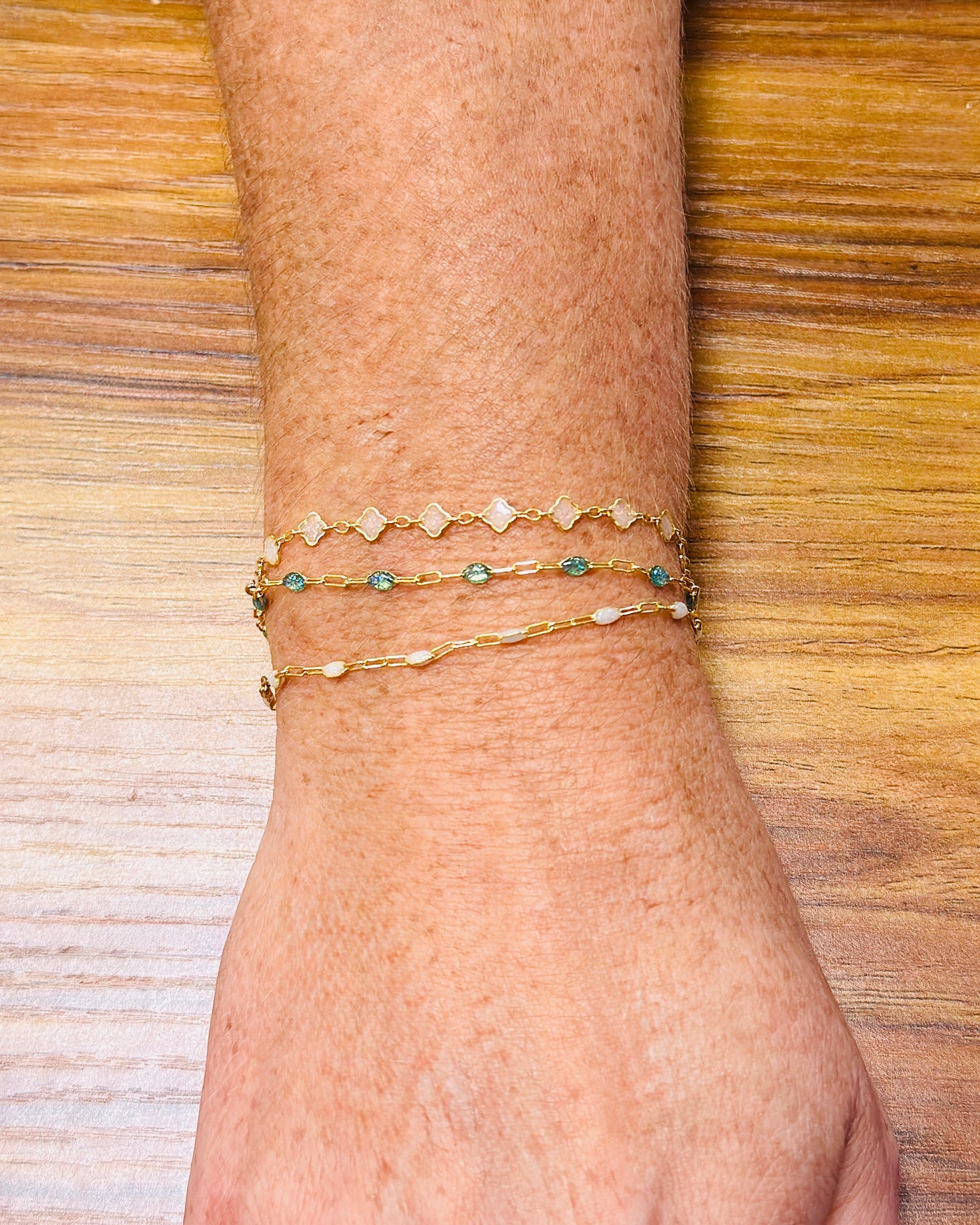 Gold filled permanent jewelry bracelets stacked on wrist featuring dainty chain designs