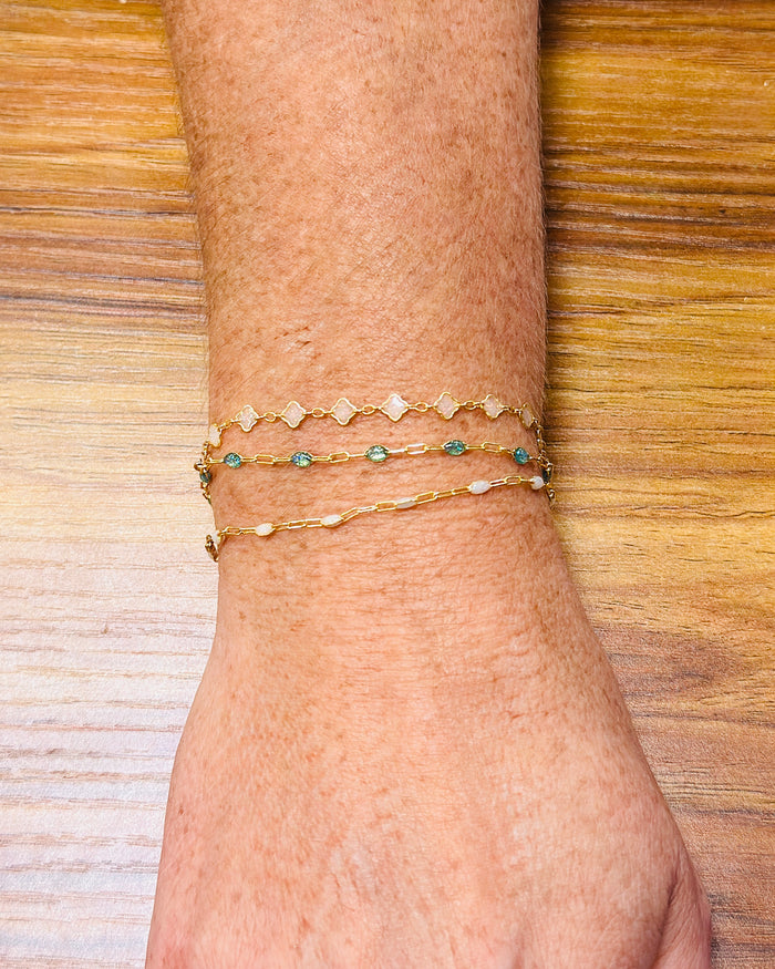 Gold filled permanent jewelry bracelets stacked on wrist featuring dainty chain designs
