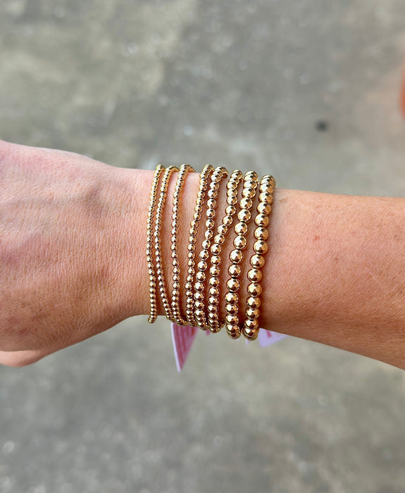 Classic 14K gold filled beaded bracelets stacked on wrist in multiple bead sizes