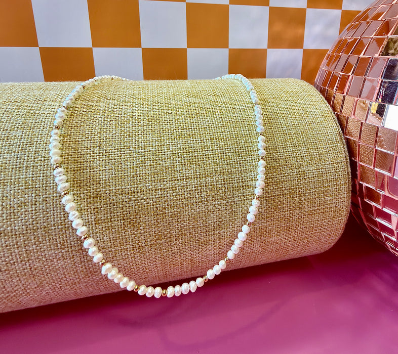 Goldie freshwater pearl necklace with gold-filled accent beads displayed on a linen jewelry stand